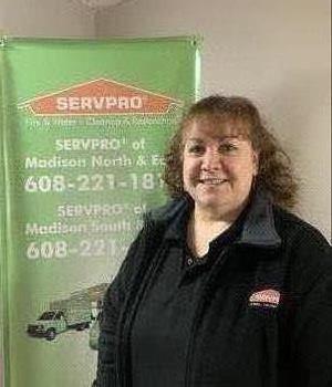 Picture of female employee Bev standing in front of the SERVPRO banner