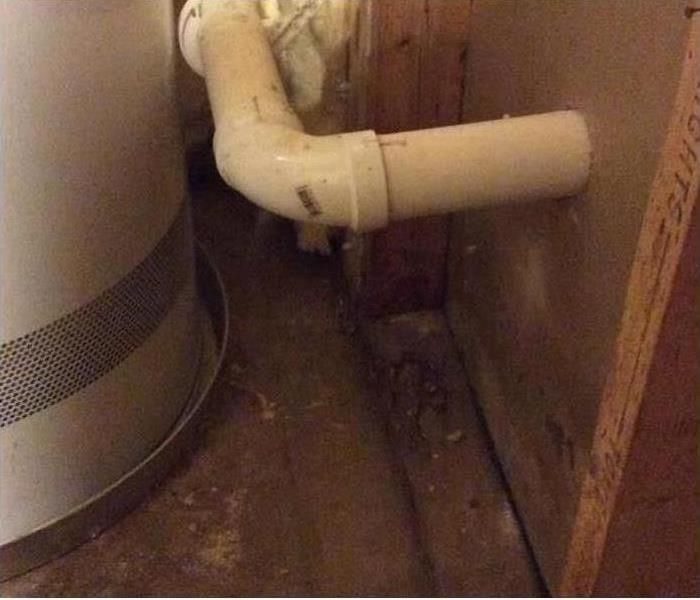 picture of a water heater that has leaked water on the basement floor