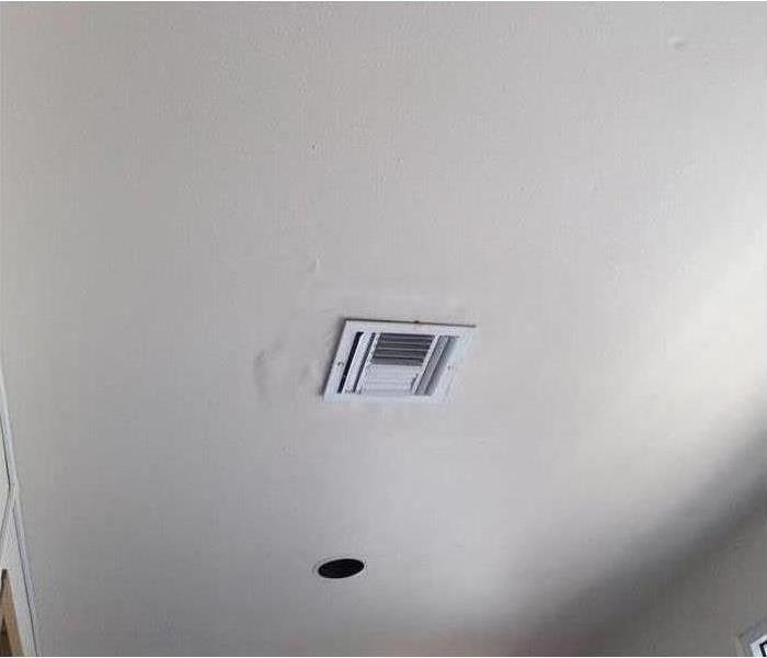picture of a ceiling where water damage is showing around the ceiling vent