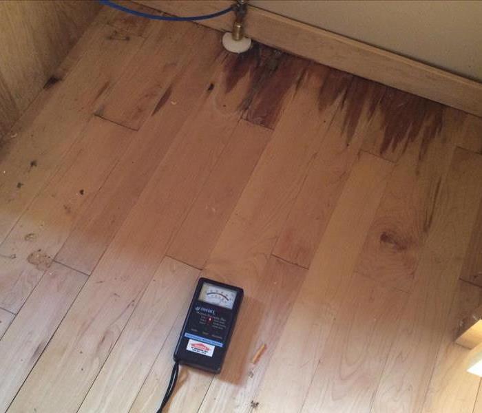 picture of the refrigerator water line and the hardwood floors that have water stains on them