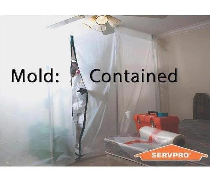 A Servpro advertisement picture of a containment set up with the words "mold contained" across the center of picture