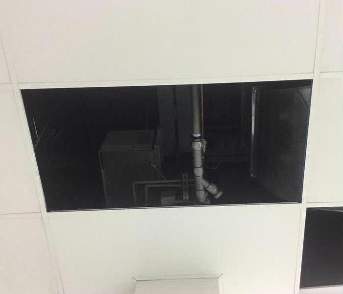 picture of a missing ceiling tile showing an exposed pipe