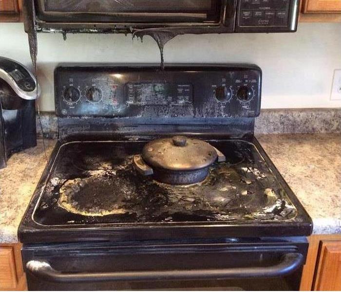 stove in a kitchen that is blackened with soot from a grease fire