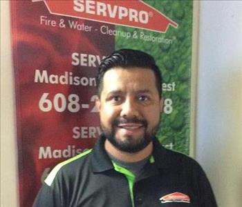 Picture of male employee Ray Garcia standing in front of a SERVPRO banner