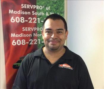 Picture of Carlos smiling in front of a SERVPRO banner