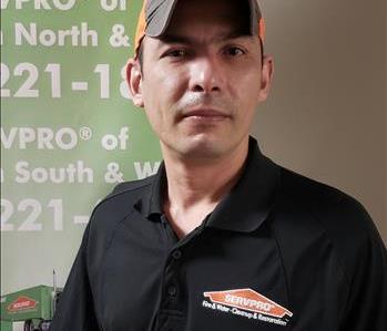Nahum Rascon standing in front of a SERVPRO banner